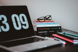 picture of a home office setup with a laptop and stack of books on a desk