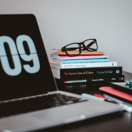 picture of a home office setup with a laptop and stack of books on a desk